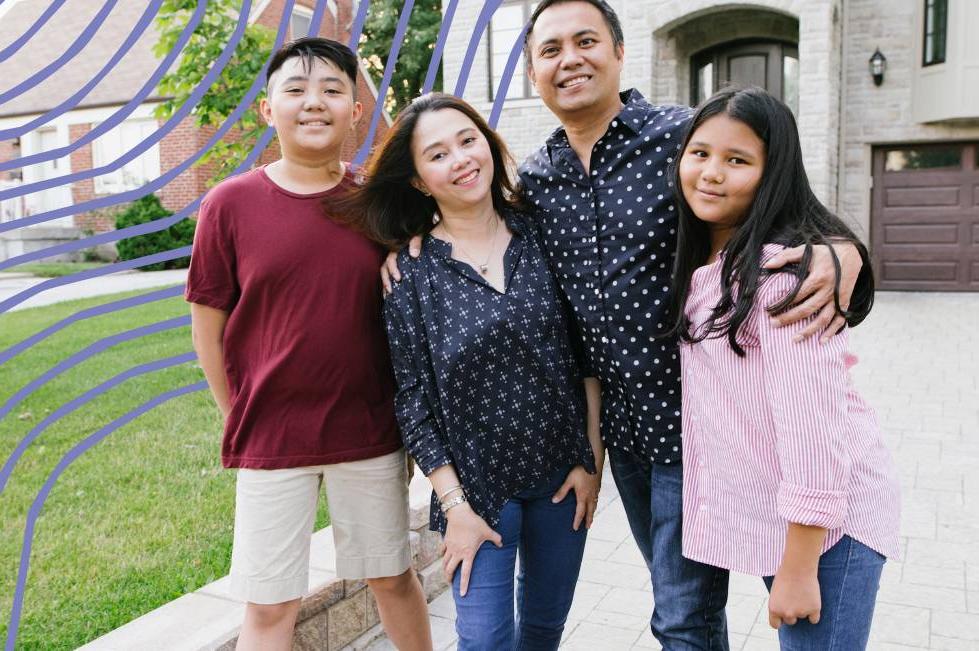 A family of four standing in front of a house